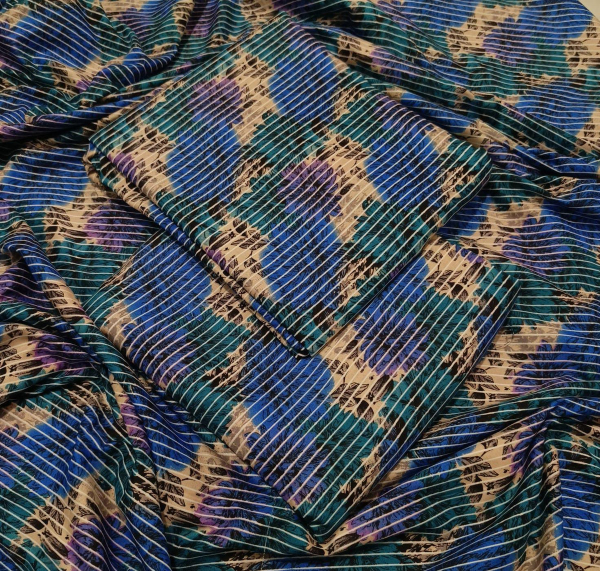 A close-up of draped fabric with a blue, teal, purple, and beige abstract pattern and fine vertical stripe texture.