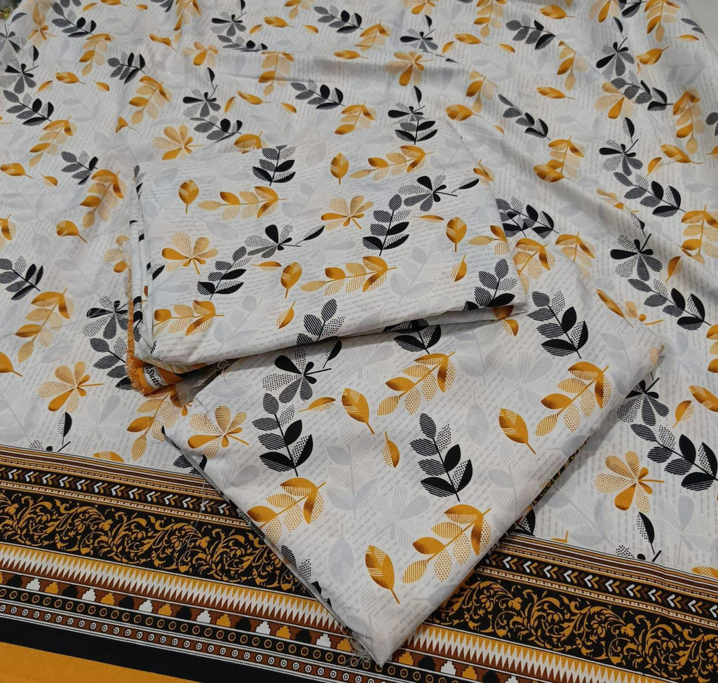 A folded piece of white fabric with a repeating pattern of mustard yellow and dark gray leaf motifs, featuring a decorative black and gold border along the bottom edge.